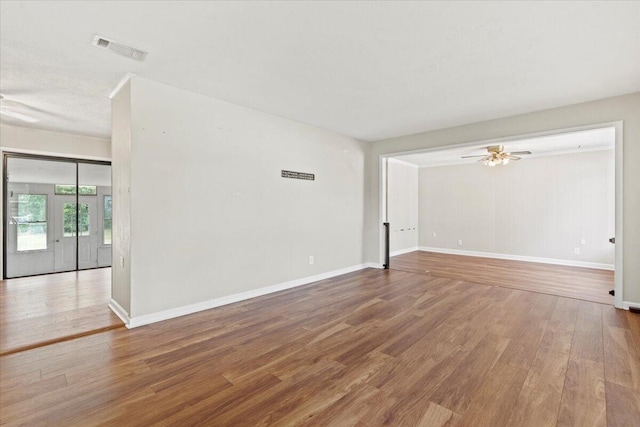 spare room with baseboards, ceiling fan, wood finished floors, and visible vents