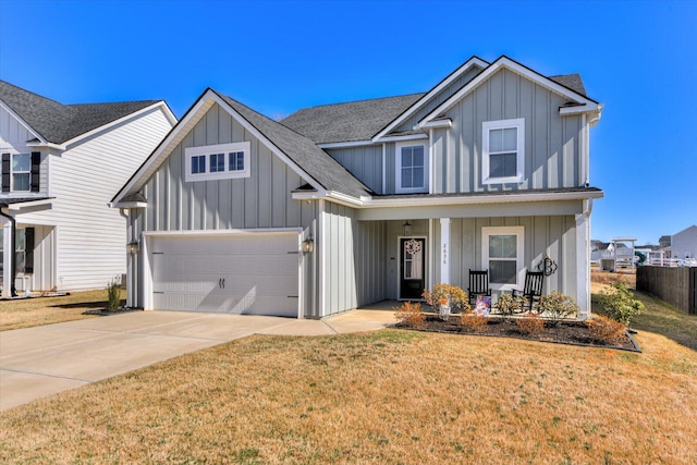 view of front of property featuring covered porch, fence, concrete driveway, a front lawn, and board and batten siding