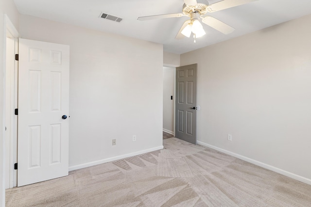 carpeted spare room with visible vents, a ceiling fan, and baseboards