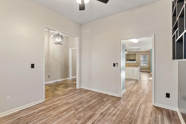 empty room featuring ceiling fan, baseboards, and light wood-style flooring