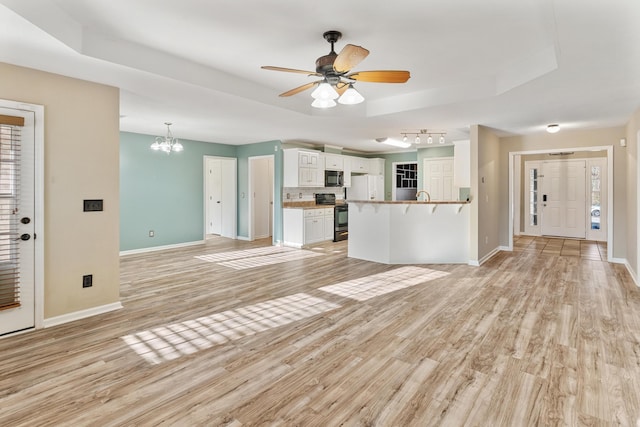 kitchen featuring a kitchen bar, a raised ceiling, black appliances, and white cabinets