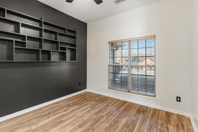 unfurnished room featuring visible vents, wood finished floors, baseboards, and ceiling fan