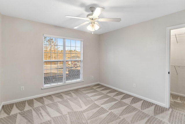 empty room with a ceiling fan, baseboards, and light carpet