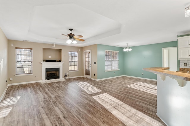 unfurnished living room featuring a wealth of natural light, a fireplace with flush hearth, and a tray ceiling