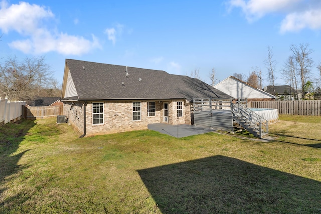 rear view of house featuring a patio, a fenced backyard, a lawn, and roof with shingles