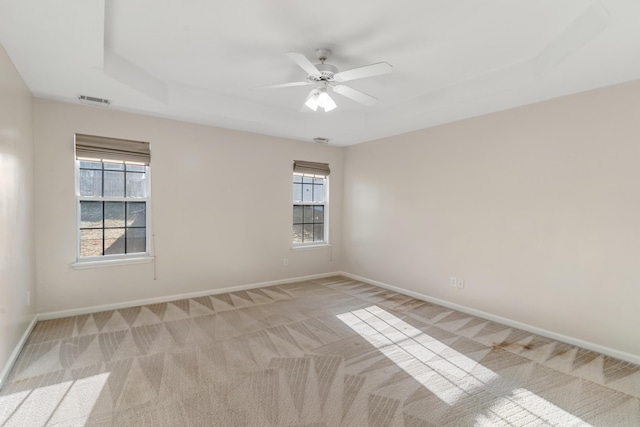 unfurnished room featuring a wealth of natural light, visible vents, baseboards, and light colored carpet