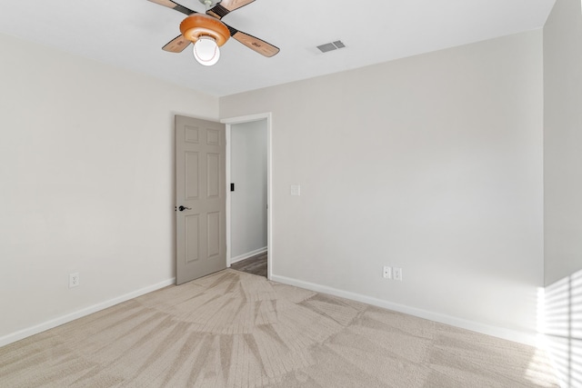 carpeted spare room with visible vents, a ceiling fan, and baseboards