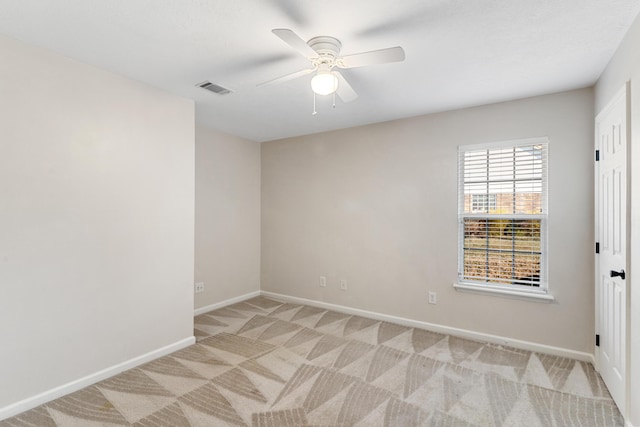 unfurnished room with a ceiling fan, light colored carpet, visible vents, and baseboards