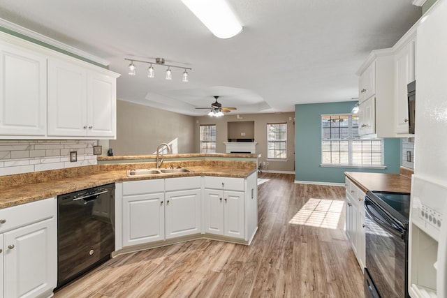 kitchen featuring a peninsula, a fireplace, a sink, black appliances, and backsplash