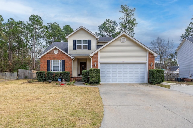 traditional-style home with a garage, brick siding, fence, driveway, and a front yard