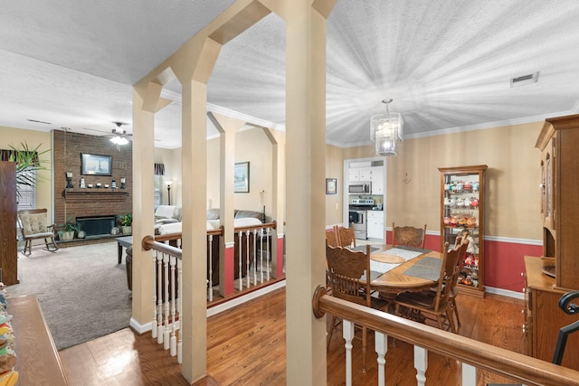 dining space with arched walkways, a fireplace, visible vents, ornamental molding, and wood finished floors