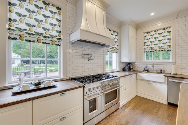 3406 W Richland Ave, Aiken, SC 29801 - kitchen featuring custom range hood, appliances with stainless steel finishes, butcher block counters, light wood-style floors, and backsplash