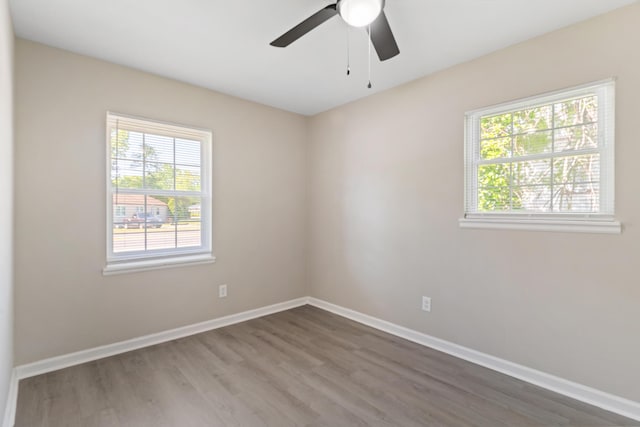 empty room featuring ceiling fan, baseboards, wood finished floors, and a healthy amount of sunlight