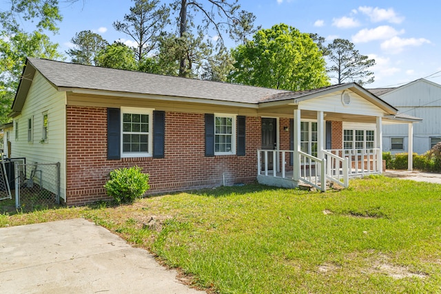 ranch-style house with covered porch, fence, a front lawn, and brick siding