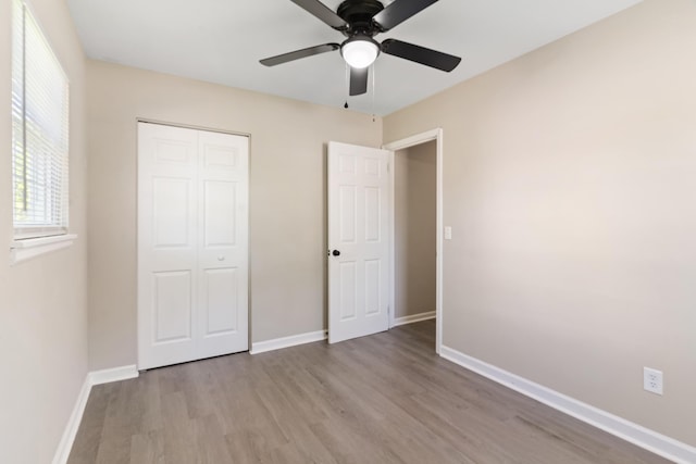 unfurnished bedroom with a closet, baseboards, a ceiling fan, and wood finished floors