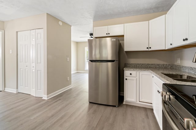 kitchen featuring light wood-type flooring, appliances with stainless steel finishes, a sink, and white cabinets
