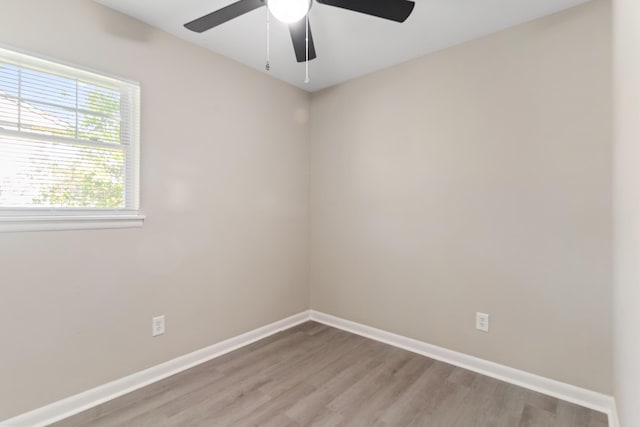 empty room featuring ceiling fan, light wood finished floors, and baseboards