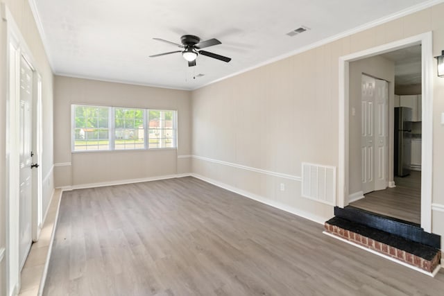 interior space featuring ornamental molding, visible vents, ceiling fan, and wood finished floors