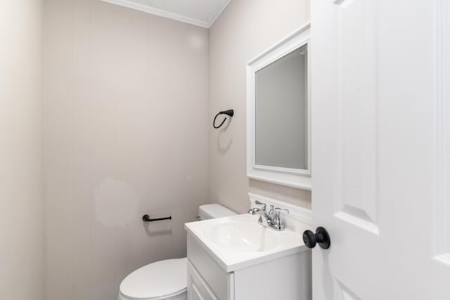 bathroom with toilet, crown molding, and vanity