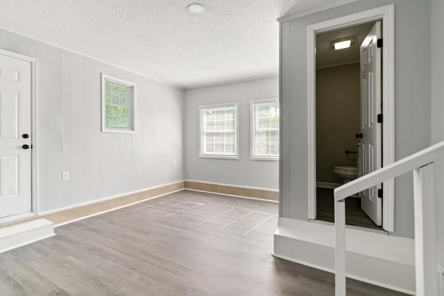 foyer entrance featuring ornamental molding, wood finished floors, and a textured ceiling