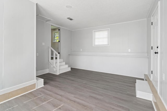 spare room with crown molding, a textured ceiling, stairway, wood finished floors, and baseboards