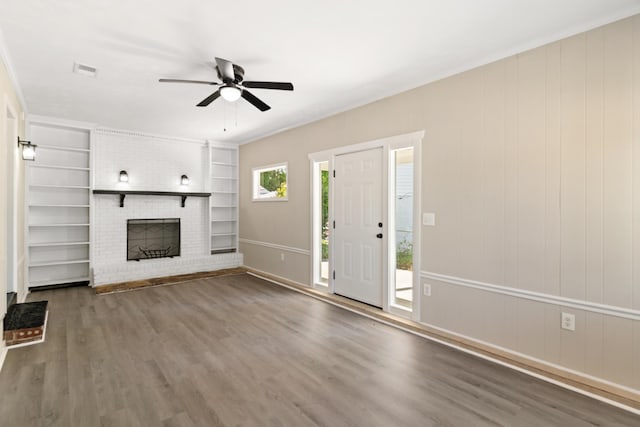 unfurnished living room with a fireplace, crown molding, visible vents, ceiling fan, and wood finished floors