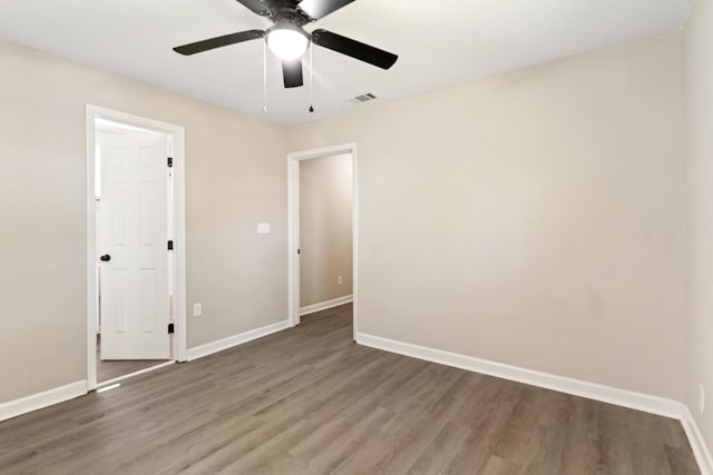 unfurnished bedroom with wood finished floors, baseboards, and visible vents