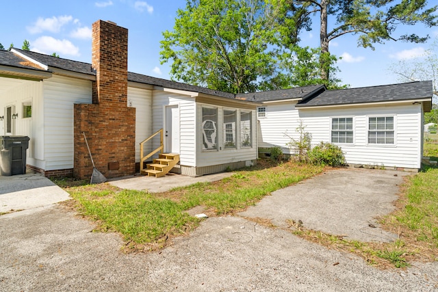 rear view of house featuring a patio area, roof with shingles, entry steps, and a chimney