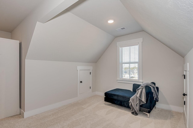 sitting room with a textured ceiling, light carpet, and vaulted ceiling