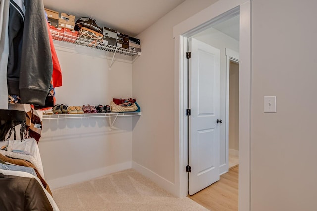 walk in closet with light carpet