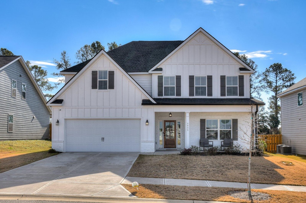view of front of home featuring covered porch, central AC, and a garage