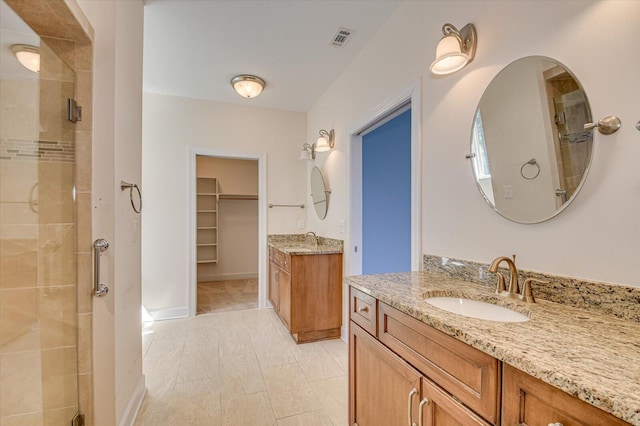 full bathroom with a stall shower, two vanities, a sink, and visible vents