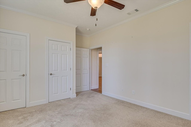 unfurnished bedroom featuring baseboards, visible vents, carpet floors, and ornamental molding