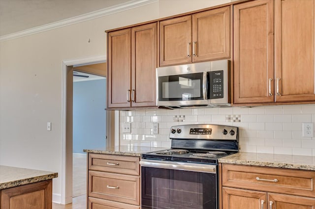 kitchen with appliances with stainless steel finishes, ornamental molding, light stone counters, and tasteful backsplash