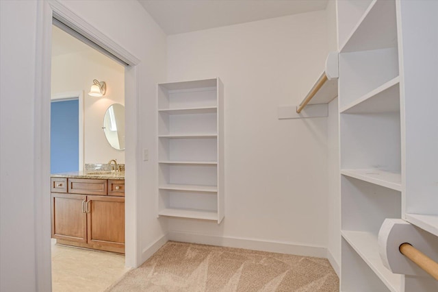 walk in closet with a sink and light colored carpet