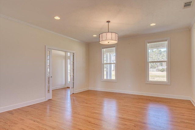 spare room featuring light wood-type flooring, visible vents, crown molding, and baseboards