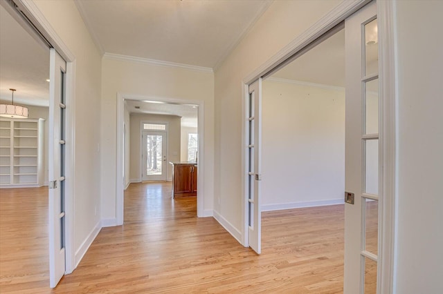 corridor with french doors, ornamental molding, light wood-style flooring, and baseboards