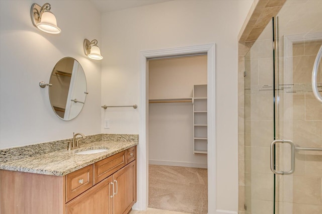 full bathroom with a shower stall, a spacious closet, baseboards, and vanity