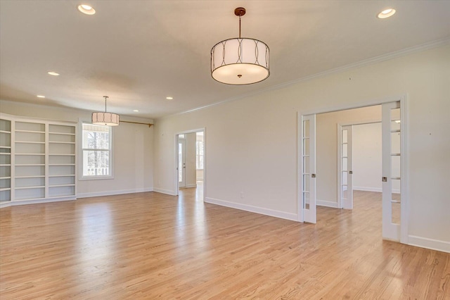 empty room featuring light wood finished floors, baseboards, and crown molding