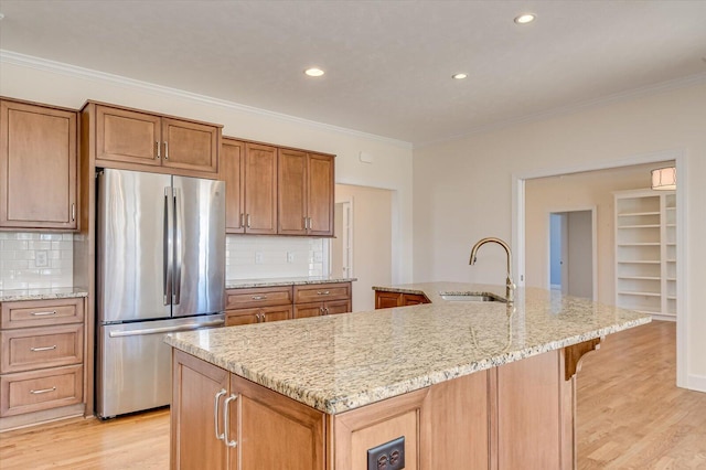 kitchen featuring a sink, light wood-style floors, crown molding, and freestanding refrigerator