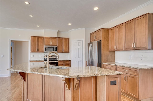 kitchen with brown cabinets, appliances with stainless steel finishes, a breakfast bar area, and a sink