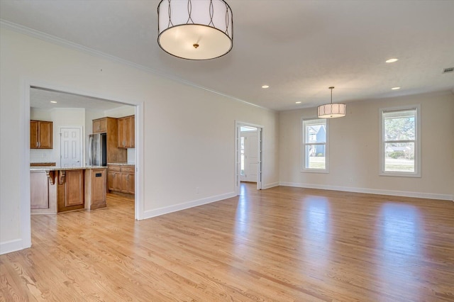 unfurnished living room featuring ornamental molding, light wood-type flooring, and baseboards