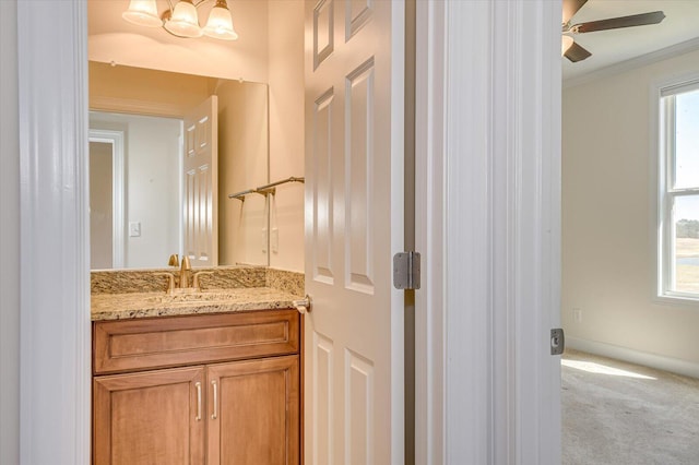 bathroom with baseboards, ceiling fan with notable chandelier, ornamental molding, and vanity