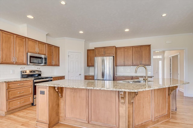 kitchen with stainless steel appliances, a breakfast bar, a sink, and light wood-style flooring