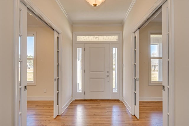 entrance foyer with baseboards, crown molding, and light wood finished floors