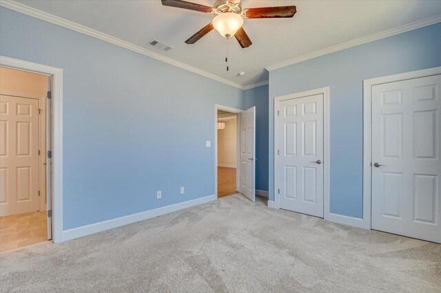 unfurnished bedroom with carpet, visible vents, crown molding, and baseboards