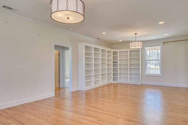 empty room with light wood-type flooring, visible vents, and crown molding