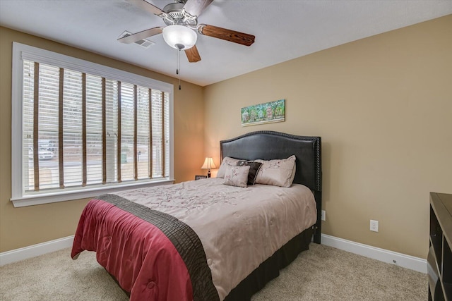 bedroom featuring baseboards, visible vents, a ceiling fan, and light colored carpet