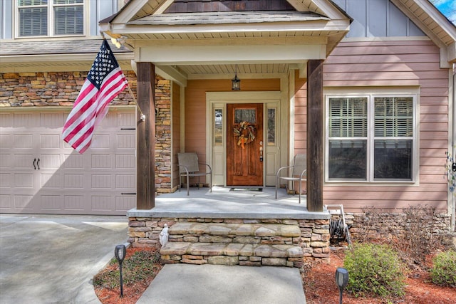 property entrance featuring driveway, a porch, board and batten siding, and stone siding