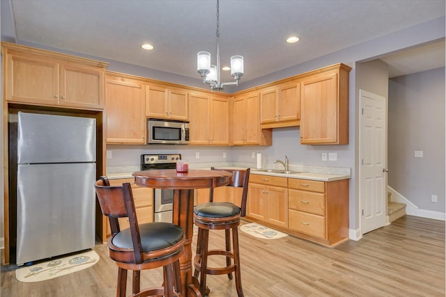 kitchen with light wood finished floors, decorative light fixtures, stainless steel appliances, light countertops, and light brown cabinets